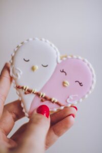 person holding white and pink birds ornament