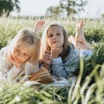 little girls lying on green grass field