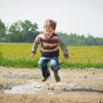boy jumping near grass at daytime