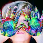 a kid with multicolored hand paint