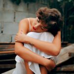 woman squatting near gray concrete wall