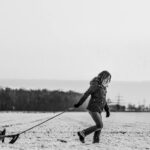 woman pulling snow sled with baby