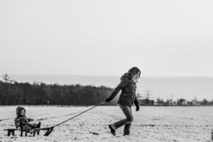 woman pulling snow sled with baby