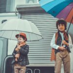two children holding umbrellas while smiling