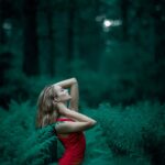 woman wearing red sleeveless dress standing near fern leaves