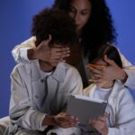 mother covering the kids eyes while they are holding the tablet