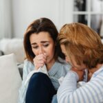 two women friends crying at home